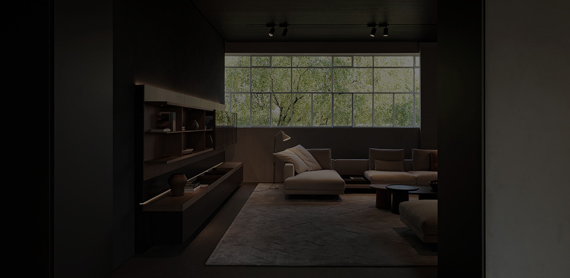 Couches and side tables are arranged in the living room with a long window across the whole wall.