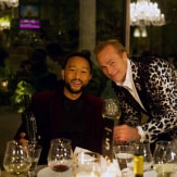 John Legend and Jean-Charles Boisset looks into the camera at the dinner table.