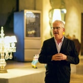 Standing up, James Suckling addresses an audience as he talks about his personal experience with SIGNATURE wine cellars, as a wine expert.
