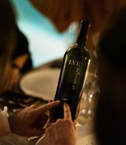 A close view of LVE wine's bottle packaging in a dim background, presumably in an evening party. 