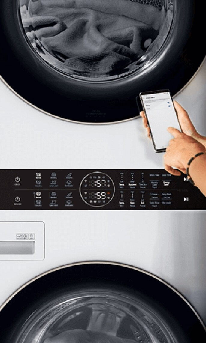 Woman using a smartphone to control the LG Studio appliances in her laundry room