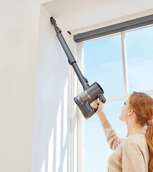 Woman Using the Crevice Tool Attachment (ABC73450101) on the LG CordZero Stick Vacuum to remove Dust from Hard-to-Reach Corner.