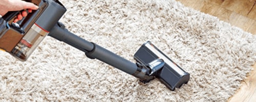 Woman using the LG Power Punch Nozzle Attachment (AGB74252404) on the LG CordZero Stick Vacuum to Get pet hair out of carpet.