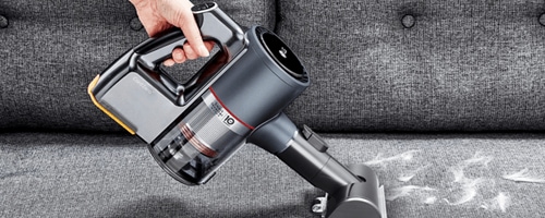 Person Using the Power Punch Nozzle Attachment (AGB74252404) on the LG CordZero as a Pet Hair Vacuum to Remove Dog Hair from Furniture.