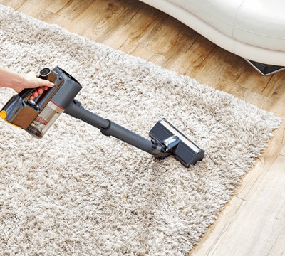 Woman using the LG Power Punch Nozzle Attachment (AGB74252404) on the LG CordZero Stick Vacuum to Get pet hair out of carpet.
