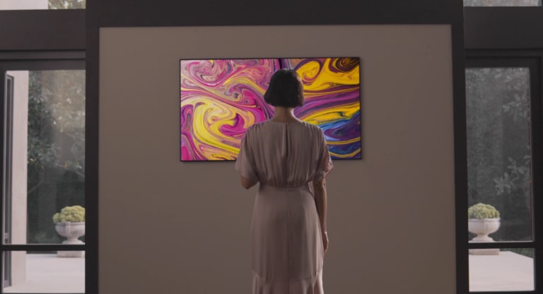 갤러리와 같은 집에 장착 된 갤러리 TV를 가진 여성은 갤러리 TV 스탠드를보고 감정적으로 그들을 봅니다