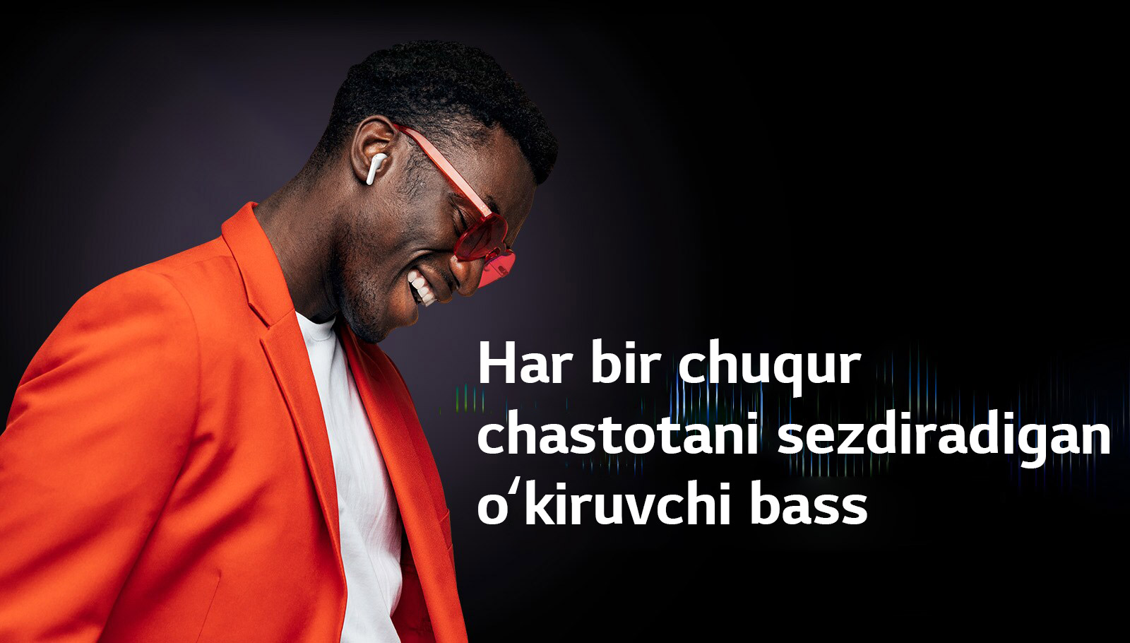 Toʻq sariq kostyumdagi erkak TONE Free quloqliklarida musiqa tinglamoqda.