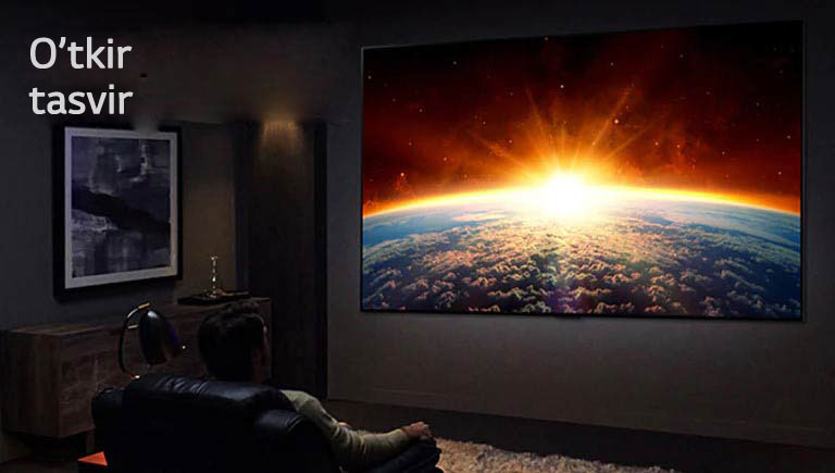 Qorongʻi xonada divanda oʻtirib, televizorda bir kishining qorli togʻ choʻqqisida turganini tomosha qilib oʻtirgan odam.