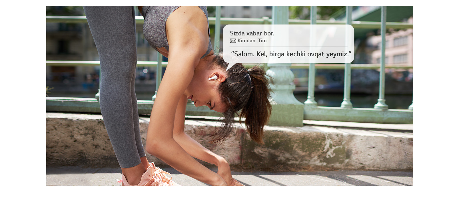 Ayol yoga mashg‘uloti vaqtida kaftlarini yerga tekkizmoqda, ayni vaqtda quloqlikda xabar eshitmoqda.