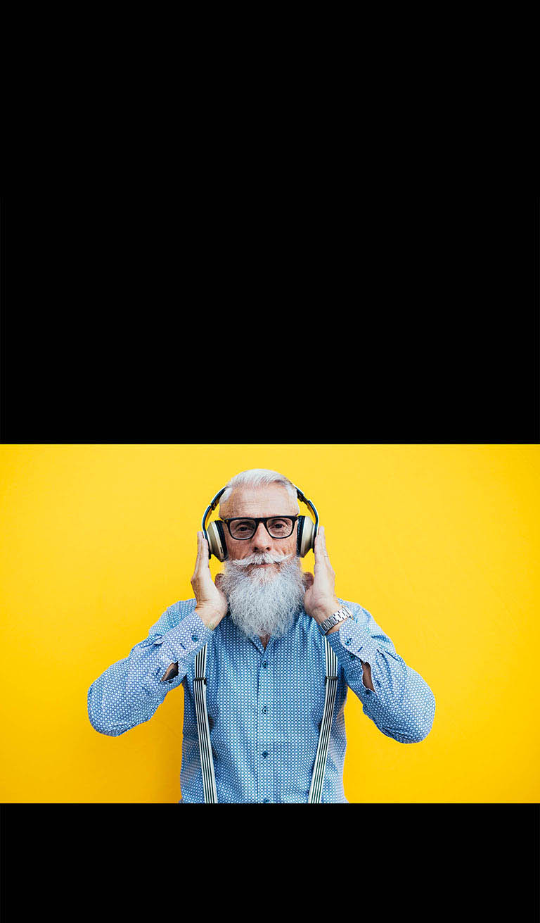 Sariq devor oldida quloqlik taqqan otaxon turibdi.