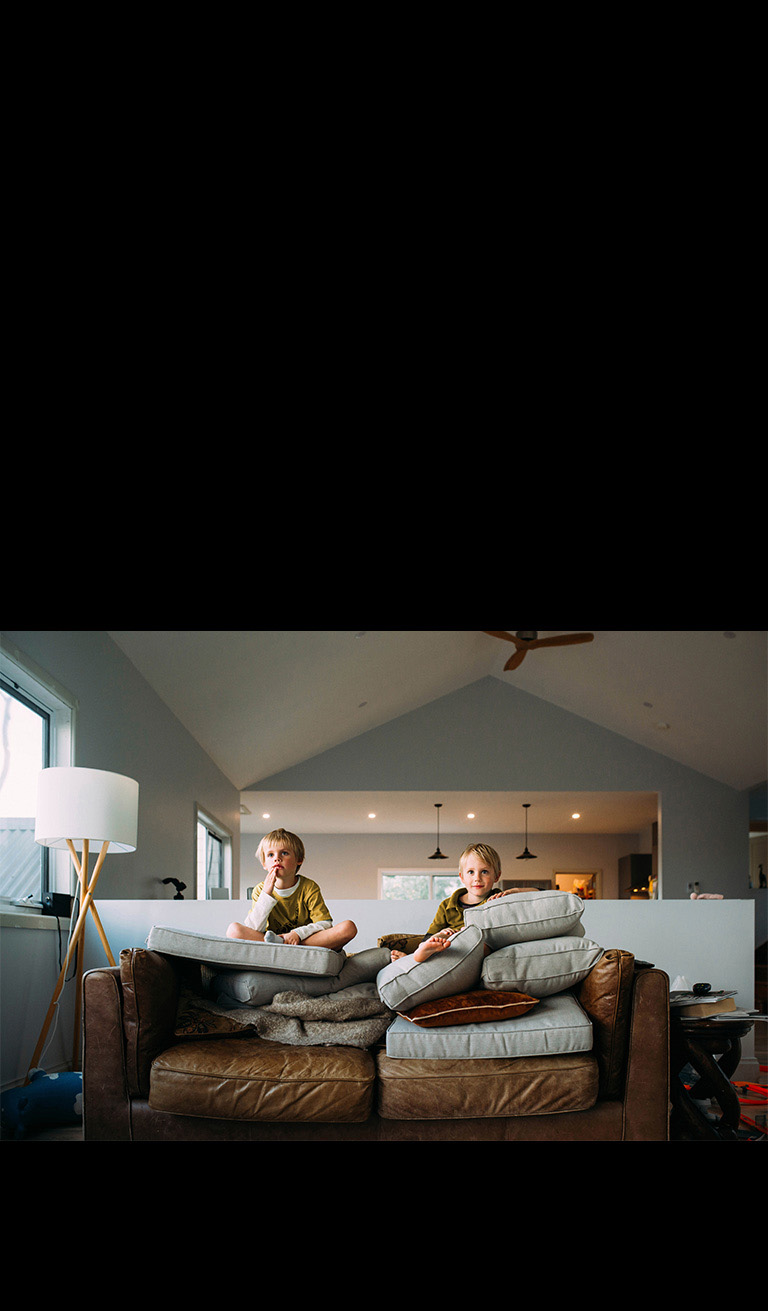 Ikki egizak bola divanda oʻtirib nimadir tomosha qilyapti.