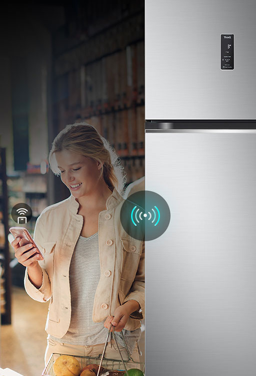 Женщина управляет холодильником lg дистанционно с помощью своего смартфона. Изображение подчеркивает интеллектуальные возможности холодильника, позволяющие пользователям управлять и регулировать настройки с мобильного устройства.