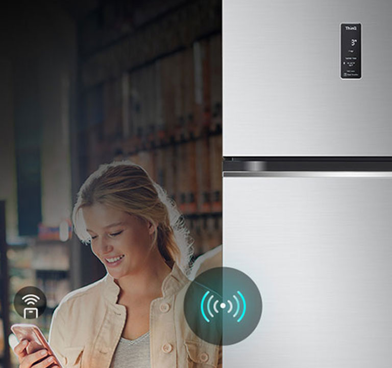 Женщина управляет холодильником lg дистанционно с помощью своего смартфона. Изображение подчеркивает интеллектуальные возможности холодильника, позволяющие пользователям управлять и регулировать настройки с мобильного устройства.