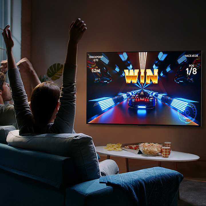 Odamlar kontroller yordamida LG OLED televizorida oʻyin oʻynamoqdalar