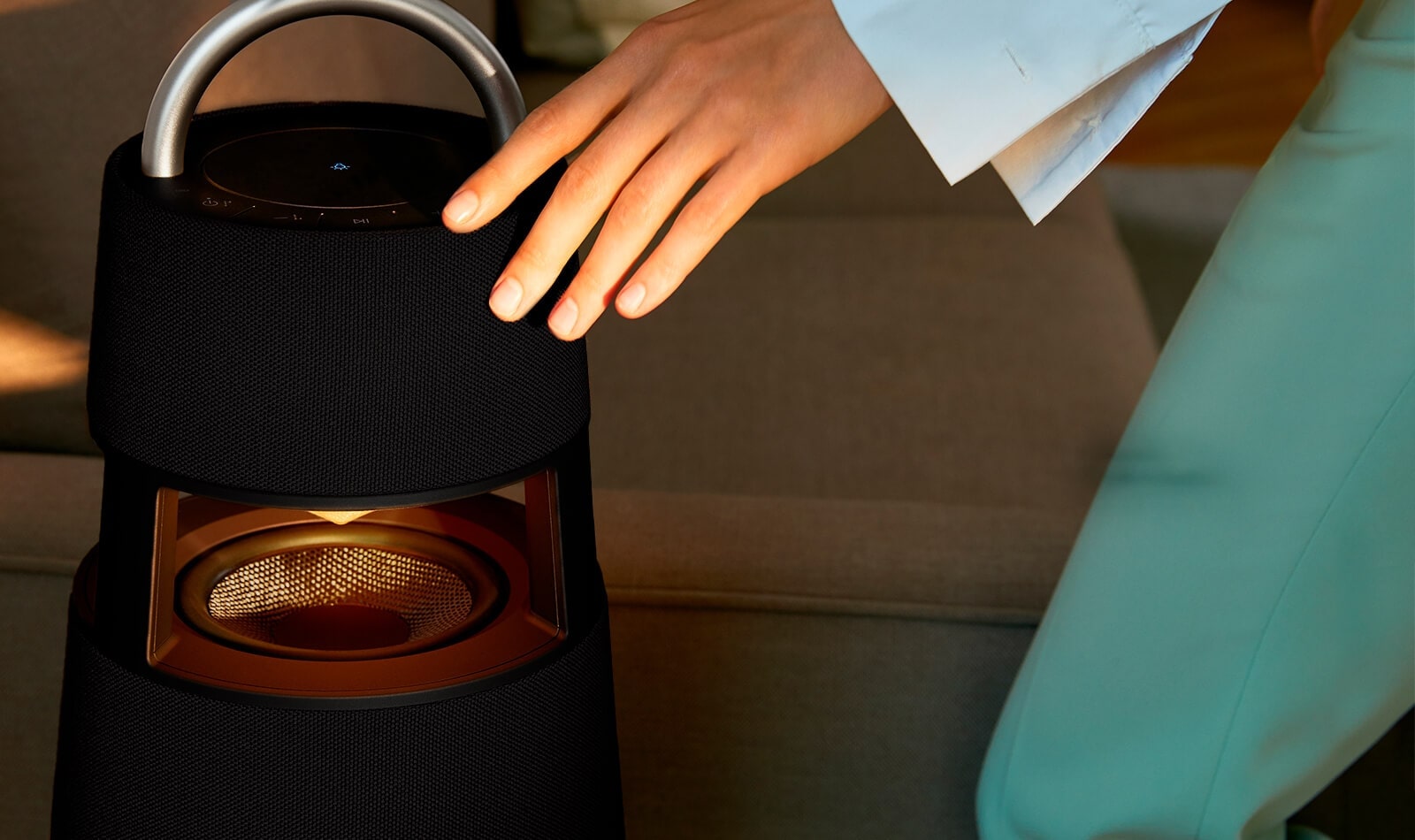 Женская рука, касающегося верхней части графитно-чёрного XBOOM 360.