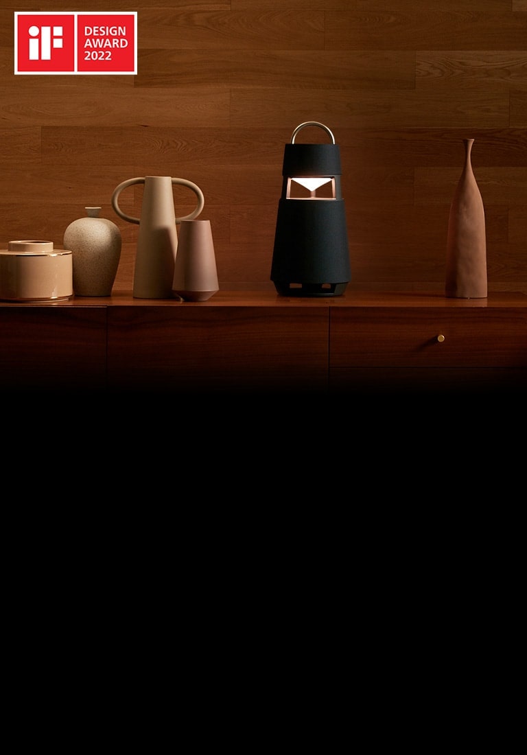 Изображение XBOOM 360 со скульптурами на полке на фоне интерьера в деревянных тонах.