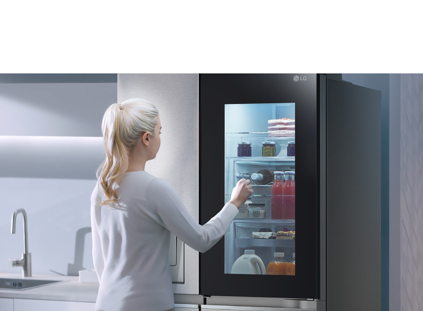 На видео видно, как женщина подходит к холодильнику InstaView и дважды стучит по нему. Внутри загорается подсветка, и она может видеть содержимое своего холодильника, не открывая дверь. Изображение увеличивается, чтобы сфокусироваться на напитках в двери, а затем уменьшается, чтобы показать женщину со спины, когда она открывает дверь и берет напиток.