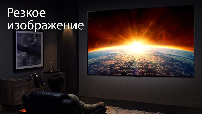 Мужчина на диване в темной комнате смотрит телевизор с изображением солнца, восходящего над землей