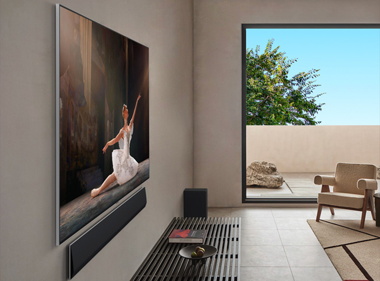 Интерьер гостиной в элитном доме. Вид сбоку под углом LG OLED TV с настенным креплением. Ясно видно, что между телевизором и стеной отсутствует зазор — он установлен вплотную, создавая эффект «картины на стене». 