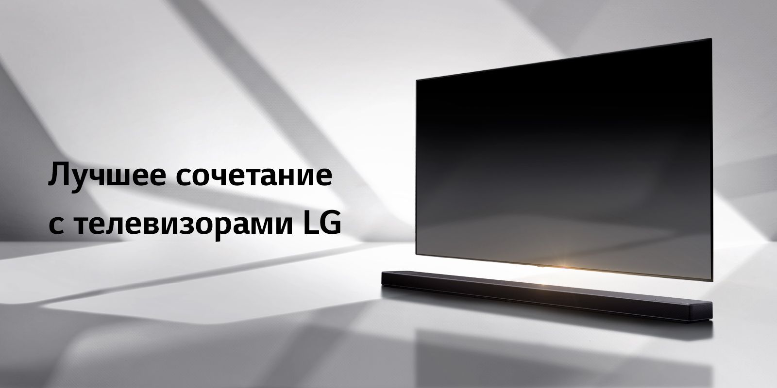 Саундбар и телевизор на белом полу с тенью, отбрасываемой снаружи справа.
