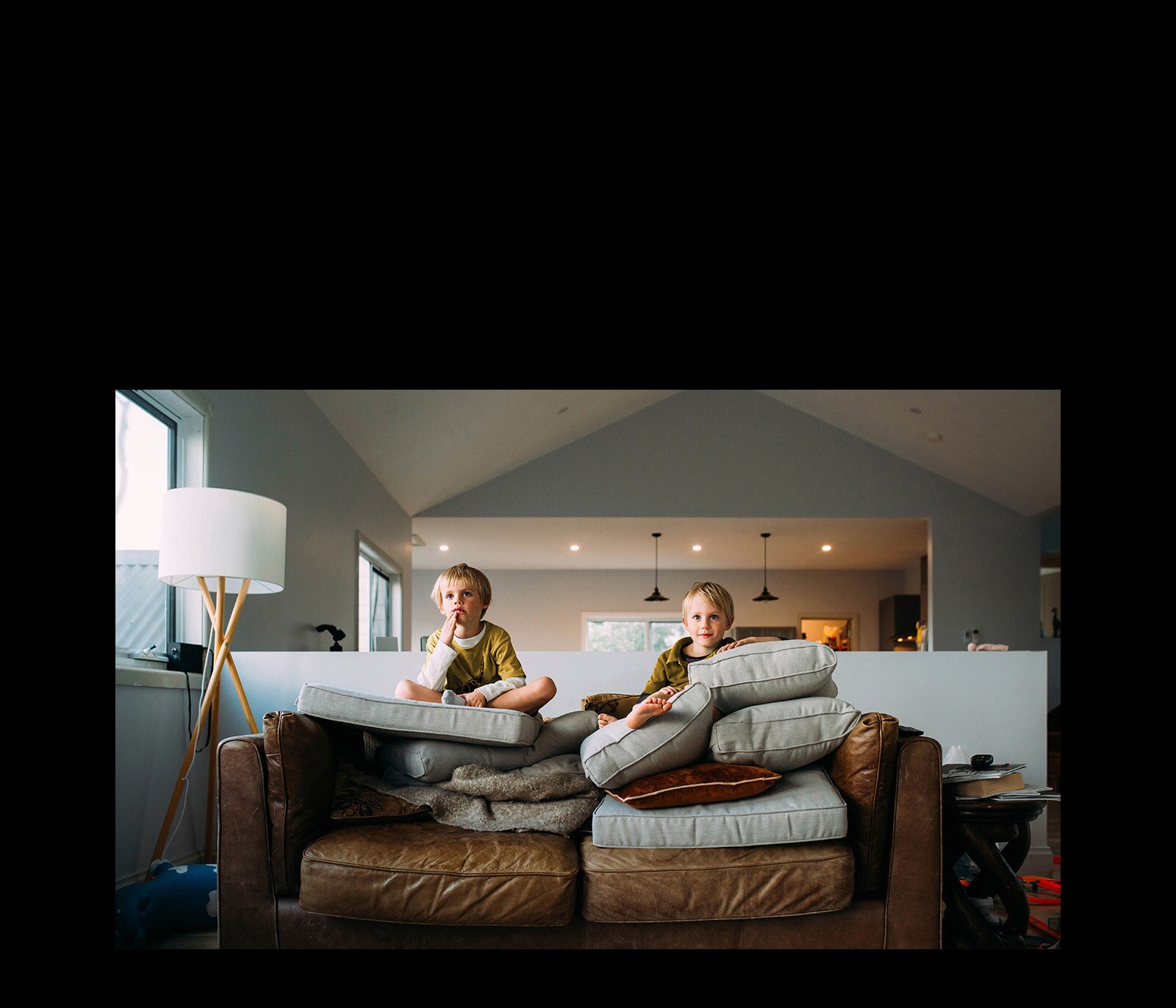 Два близнеца смотрят что-то, сидя на диване.