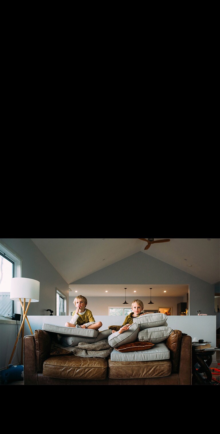 Два близнеца смотрят что-то, сидя на диване.