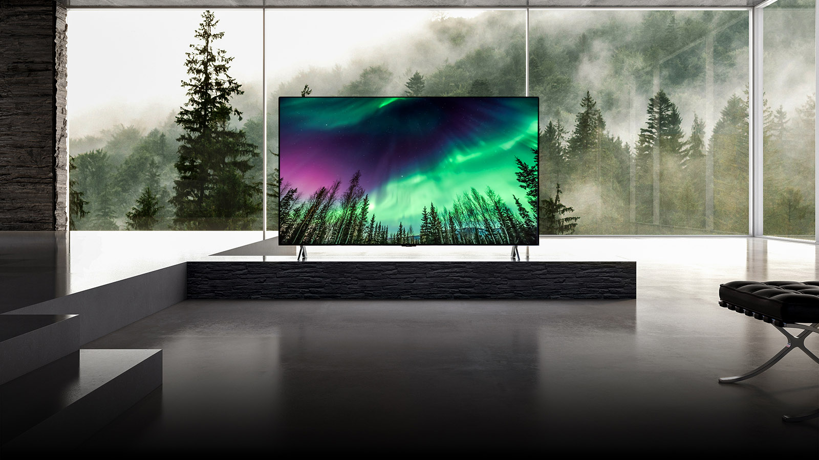 Камера перемещается от крупного плана верхней части телевизора вниз к крупному плану передней части телевизора. На экране телевизора зеленое северное сияние. Камера отдаляется, теперь на экране просторная гостиная. Гостиная в основном серого цвета, а за окном виден лес.