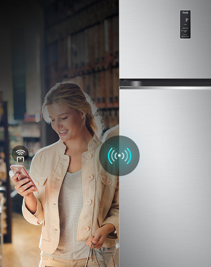 Женщина управляет холодильником lg дистанционно с помощью своего смартфона. Изображение подчеркивает интеллектуальные возможности холодильника, позволяющие пользователям управлять и регулировать настройки с мобильного устройства.	