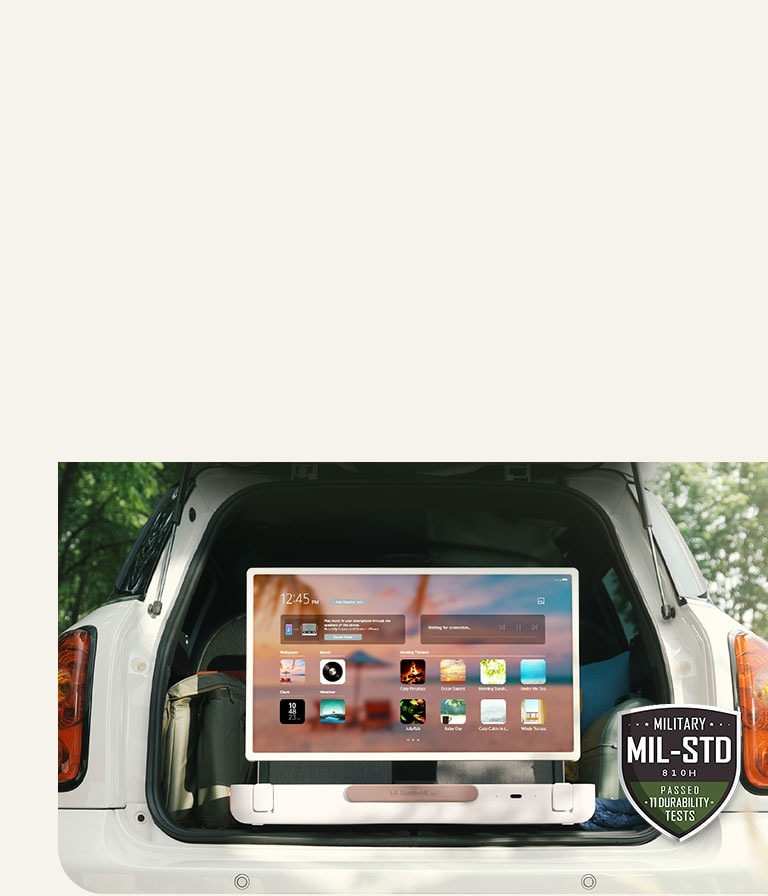 Mặt trước của LG StanbyME Go. Sản phẩm được đặt trên ô tô, màn hình xoay ngang hiển thị màn hình chính. Ở phía dưới bên trái của hình ảnh, biểu tượng thông số quân sự được hiển thị.