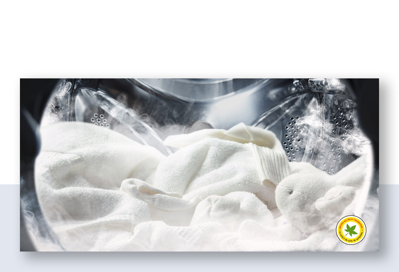 Hình ảnh một chiếc áo choàng trắng mềm mại và thú nhồi bông trong làn hơi nước trong lồng giặt của máy giặt.