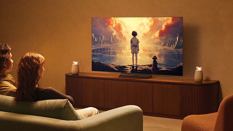 Một cặp đôi ngồi trên ghế sofa xem TV có kết nối TV qua Bluetooth bằng LG XBOOM 360 XO2T.