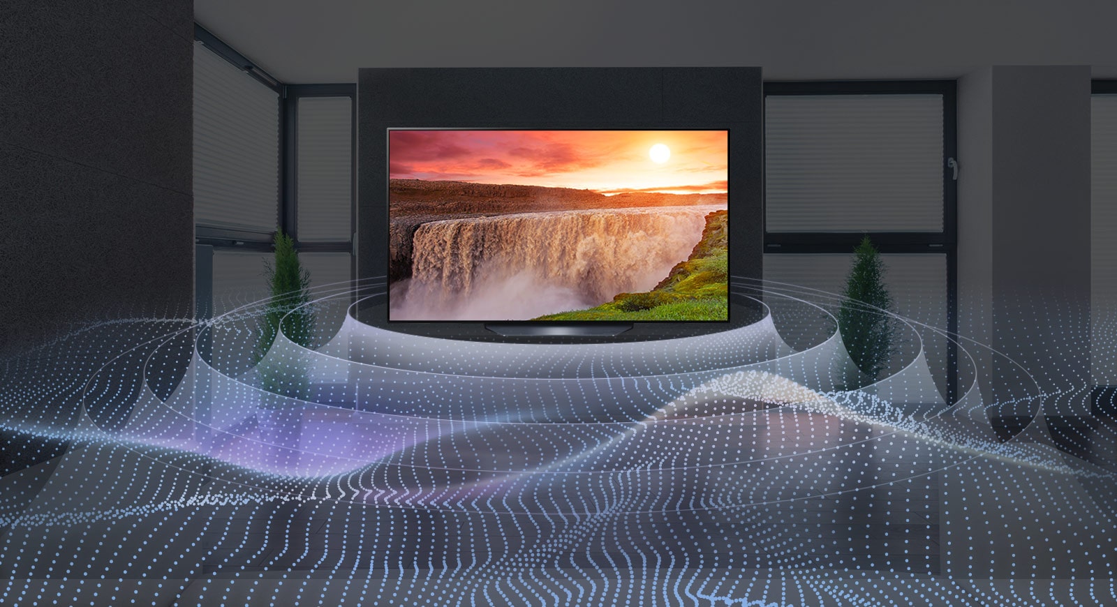 Một TV lớn màn hình phẳng trong phòng tối với thác nước rực rỡ lúc hoàng hôn hiển thị trên màn hình. Sóng phát ra từ TV theo dạng hình tròn thể hiện âm thanh vòm ảo.