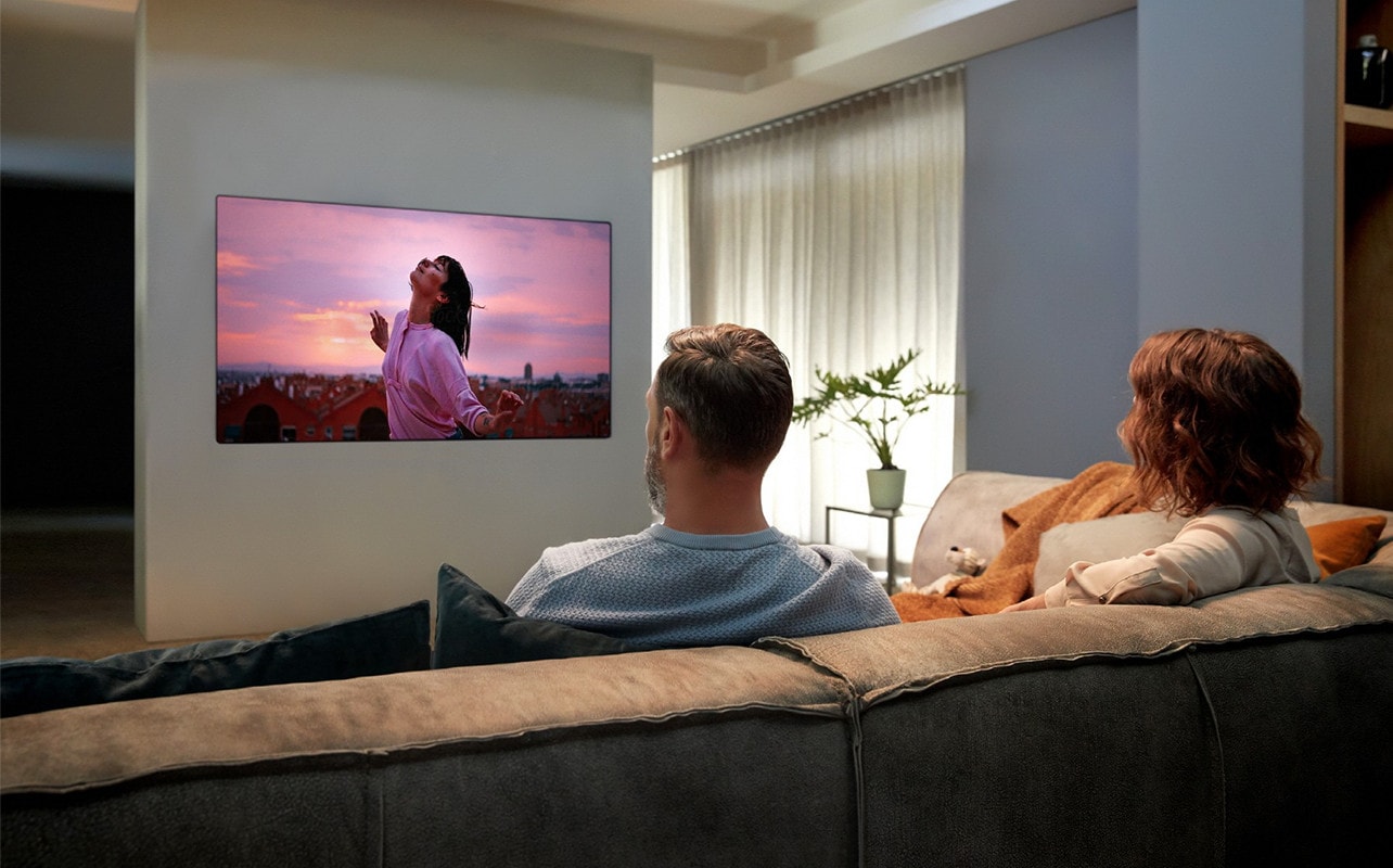 một cặp đôi đang xem TV trên ghế dài trong phòng khách