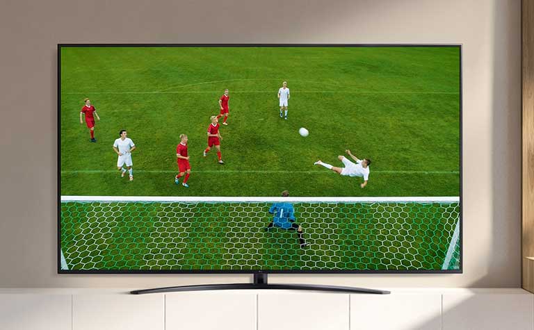 A TV screen playing a video of a soccer player making a goal during a soccer game. (play the video)