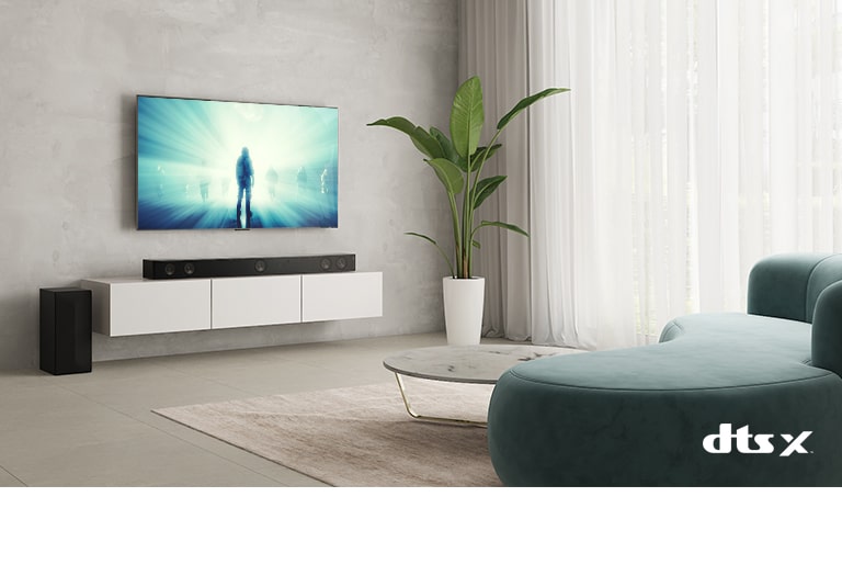 A TV LG está na parede de uma sala de estar. Um filme está sendo exibido na tela da TV. A Sound Bar LG está diretamente abaixo da TV, sobre um rack bege, com uma caixa de som à esquerda. O logotipo Dolby Atmos Virtual aparece no canto inferior direito da imagem.