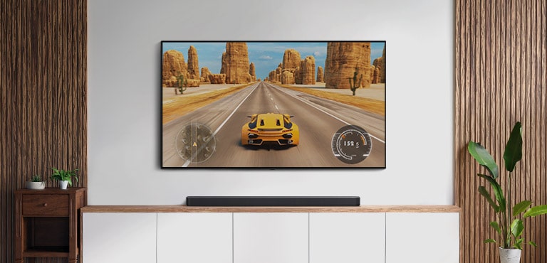 Há uma TV e uma barra de som na sala de estar. Um jogo de corrida de carros aparece na tela da televisão. (reproduza o vídeo)