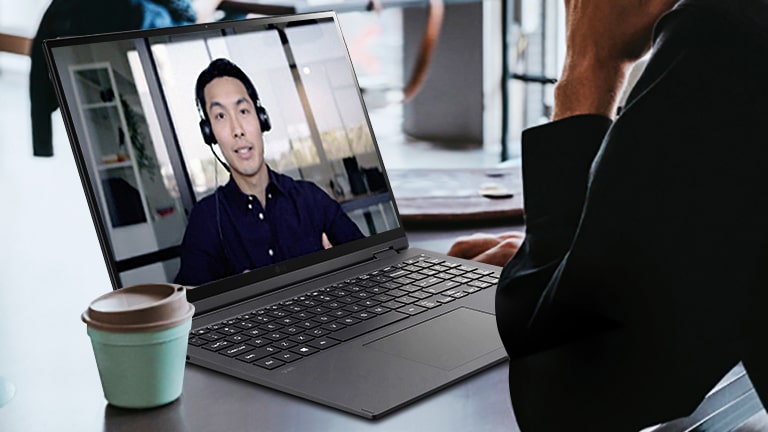 L’image montre une scène où un homme participe à une vidéoconférence dans un café.