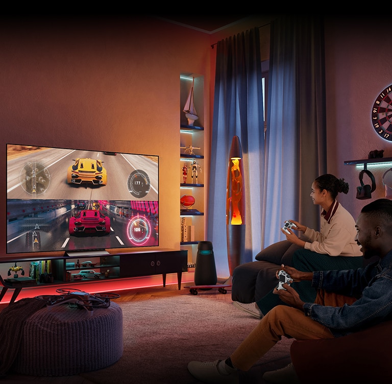 Hombres y mujeres sentados en el sofá disfrutan juntos de los juegos de carreras en la televisión.