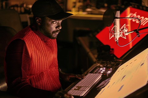 will.i.am bir stüdyoda monitörlere bakarak çalışıyor.