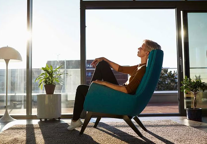 A woman relaxing in an armchair and admiring the view from her home