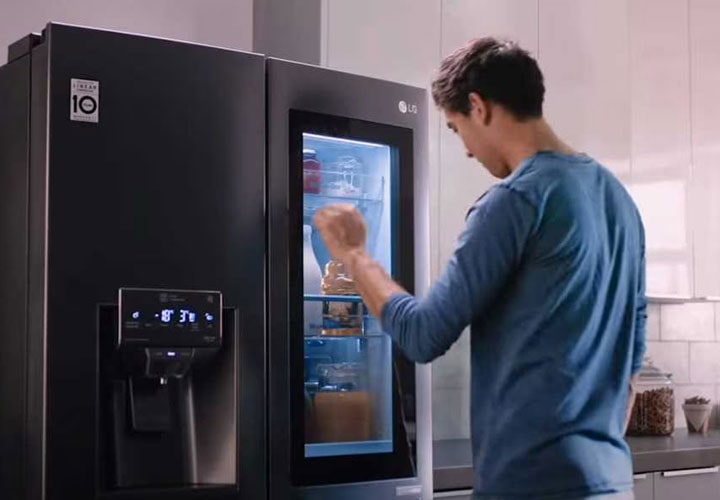 A man utilising the two-knock system on the mirrored glass panel revealing the content of the LG Instaview Door-In-Door Refrigerator.