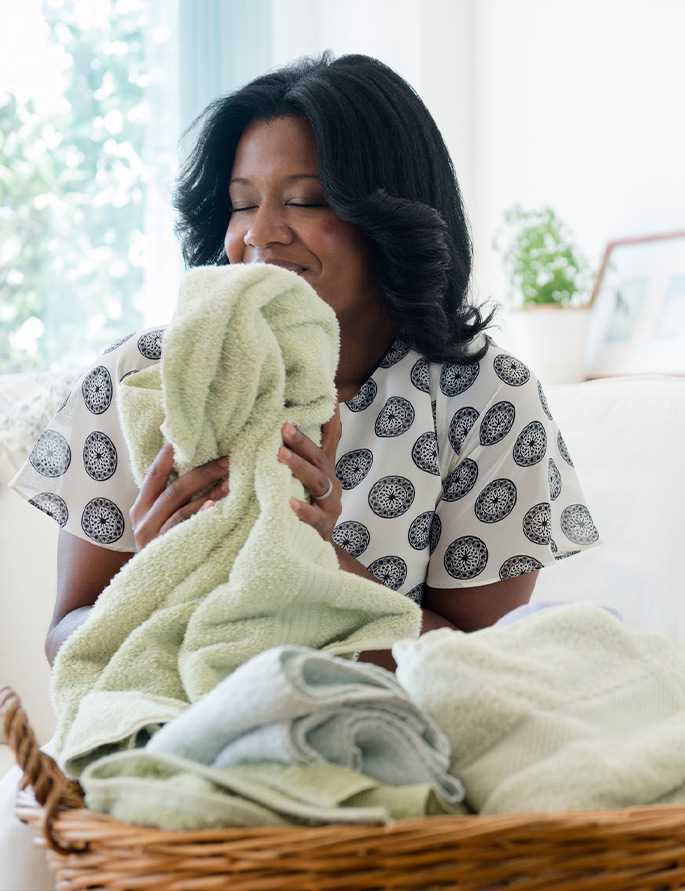 A woman smells fresh laundry from her easy care washing machine.