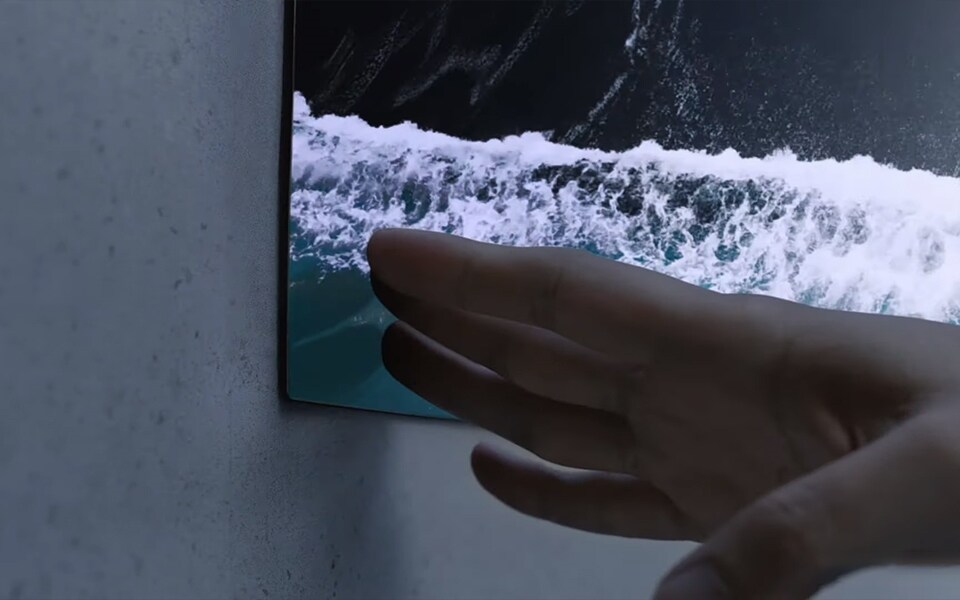 A hand touches an ultra-thin LG OLED TV.