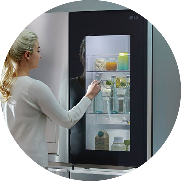 A woman is peering inside the LG Dios refrigerator through InstaView.