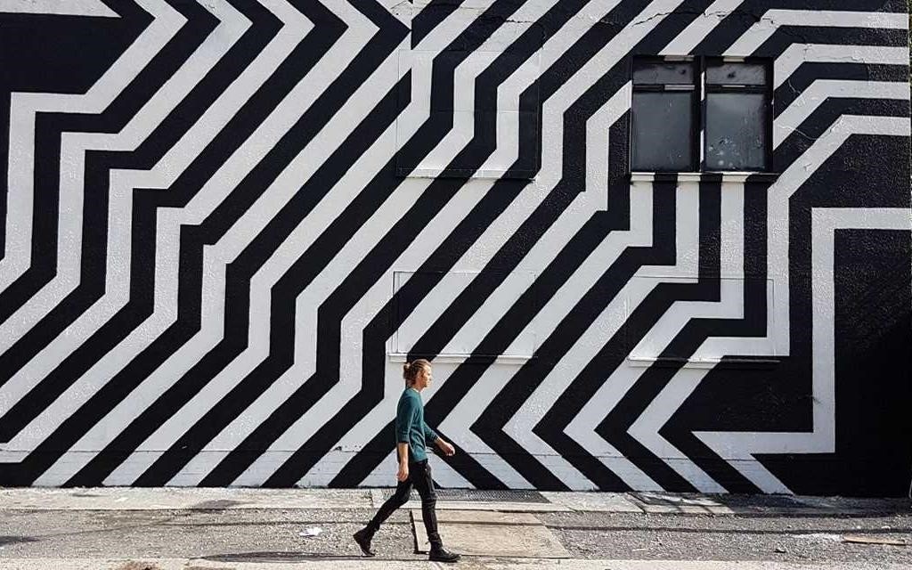 Procestujte Berlín: Muž procházející kolem černo-bílé malby pouličního umění v Berlíně.  
