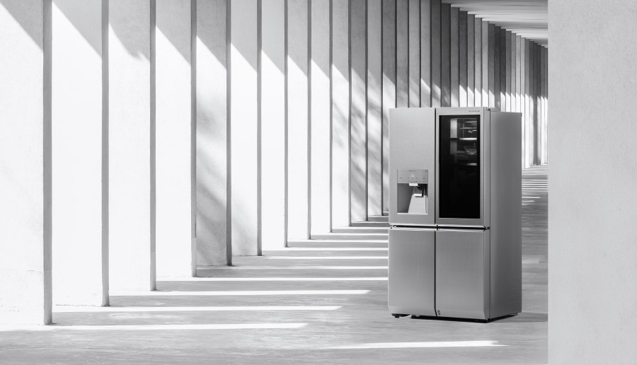 Der LG SIGNATURE Kühlschrank steht, teils im Sonnenlicht und teils im Schatten, in einem Säulengang.