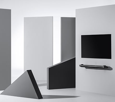 Der LG SIGNATURE OLED TV W ist an einer Wand angebracht, umgeben von geometrischen Figuren.
