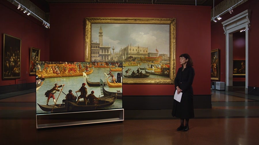 A docent is explaining about the Giovanni Antonio Canal's Bucentaur's return to the pier by the Palazzo ducale.