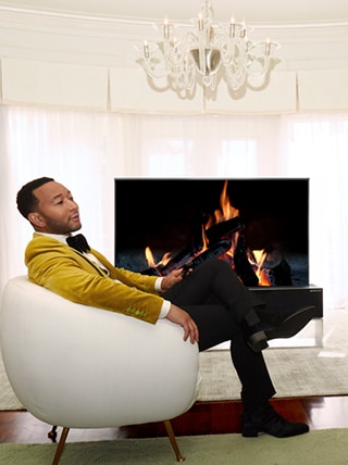 John Legend che si rilassa davanti a un TV arrotolabile.
